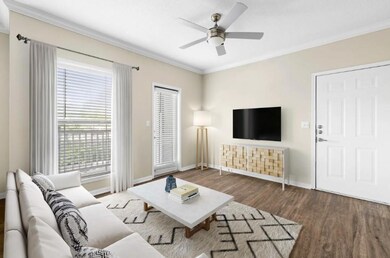 Living room with wood finished floors, a ceiling fan, baseboards, and ornamental molding