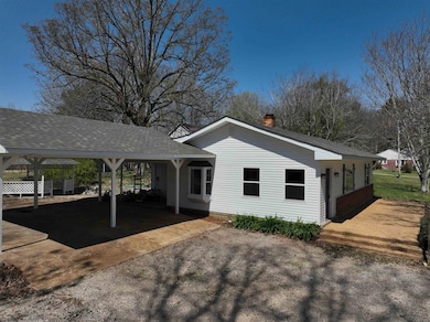 View of property exterior with an attached carport, a chimney, and roof with shingles