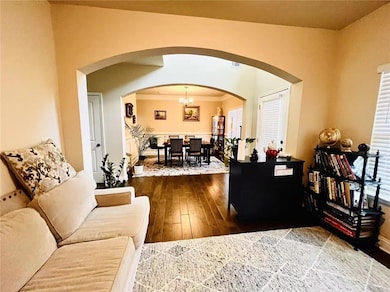 Living area with arched walkways, hardwood / wood-style floors, and a chandelier