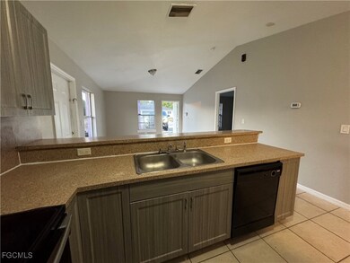 Kitchen with electric stove, lofted ceiling, a peninsula, light tile patterned floors, and black dishwasher