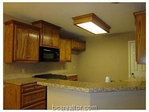 Kitchen featuring a peninsula, brown cabinetry, li