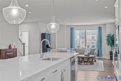 Kitchen with white cabinetry, open floor plan, light wood finished floors, light stone counters, and recessed lighting