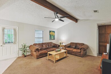 Living room featuring ceiling fan, lofted ceiling with beams, a textured ceiling, and carpet flooring