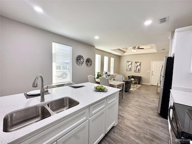 Kitchen with a tray ceiling, freestanding refrigerator, black range with electric stovetop, white cabinetry, and recessed lighting