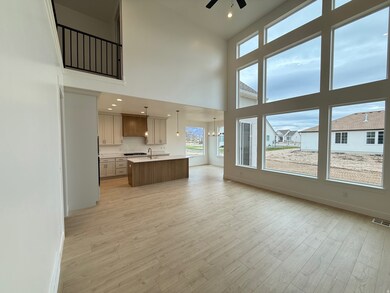 Unfurnished living room featuring recessed lighting, light wood-style flooring, a towering ceiling, a chandelier, and ceiling fan