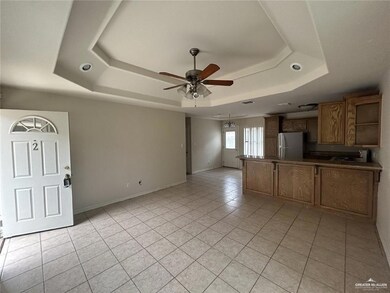 Unfurnished living room featuring a raised ceiling, ceiling fan, and light tile patterned floors