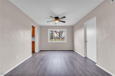 Spare room featuring dark wood-style flooring, ceiling fan, and baseboards