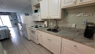 Kitchen with white appliances, white cabinets, light stone countertops, a wall unit AC, and open shelves