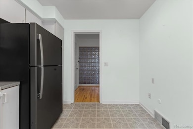 Kitchen with freestanding refrigerator and white cabinetry