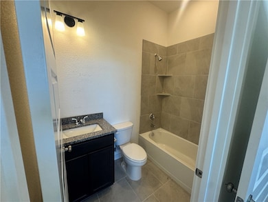 Full bath with vanity, shower / bathtub combination, light tile patterned flooring, and a textured wall