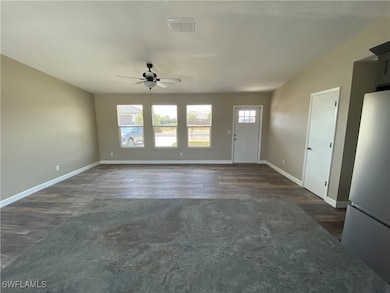 Unfurnished living room with ceiling fan, dark woo