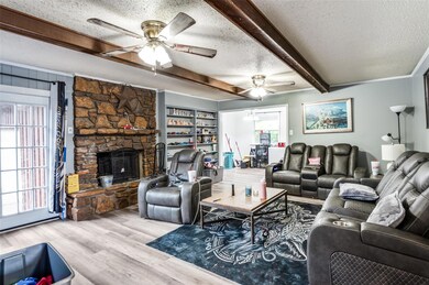 Living room with light wood-type flooring, ceiling fan, a fireplace, and a textured ceiling