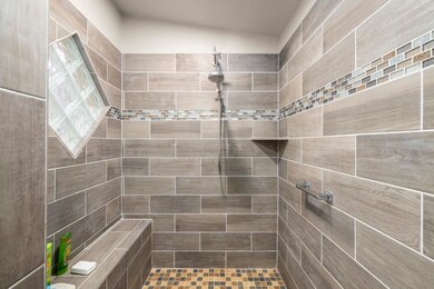 Primary Bathroom tiled shower with a bench, glass block window and dual shower heads