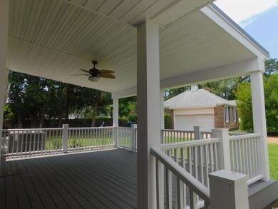 Wooden deck featuring a garage and ceiling fan