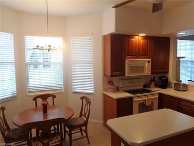 Kitchen featuring white appliances, light countertops, light tile patterned floors, a chandelier, and a center island