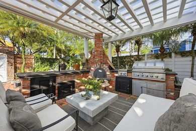 View of patio with a pergola, exterior kitchen, and an outdoor brick fireplace
