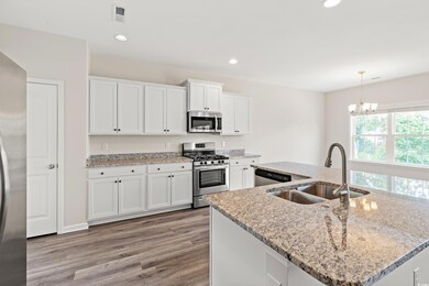Kitchen with appliances with stainless steel finishes, a sink, light wood finished floors, white cabinetry, and recessed lighting