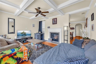 Living area featuring coffered ceiling, wood finished floors, ceiling fan, beamed ceiling, and a premium fireplace