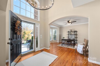 Stunning two-story foyer with modern chandelier and open sight lines into the office and main living areas.