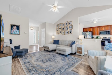Living room with a ceiling fan, vaulted ceiling, and light wood-style floors