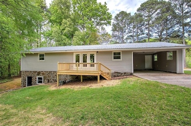 Rear view of property with asphalt driveway, a yard, a metal roof, and a carport