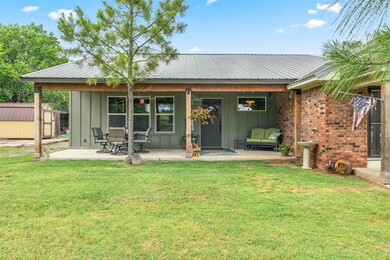 Back of property with board and batten siding, a yard, metal roof, and brick siding