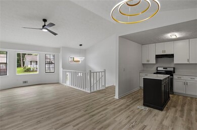 Kitchen featuring stainless steel range oven, under cabinet range hood, a textured ceiling, open floor plan, and light wood-type flooring