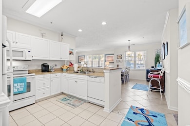 Kitchen featuring sink, white appliances, crown molding, white cabinetry, and kitchen peninsula