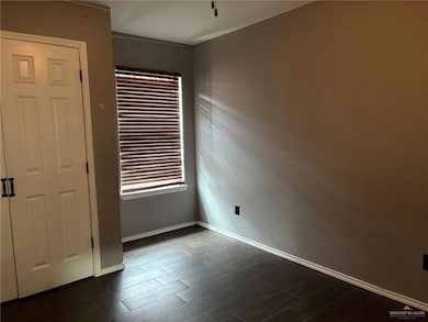 Spare room with dark wood-type flooring and baseboards