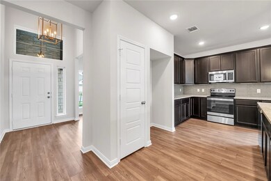 Kitchen featuring stainless steel appliances, backsplash, dark brown cabinets, light wood-style floors, and recessed lighting