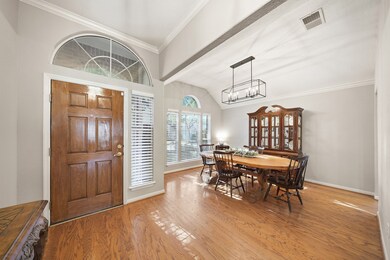 Expansive view from the foyer into the formal dining room, highlighting the seamless wood floors, vaulted ceiling, and ample natural light from the large windows.