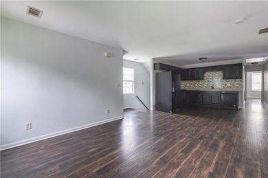 Unfurnished living room with dark wood-style flooring and baseboards