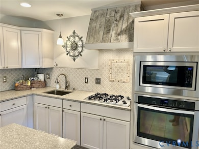 Kitchen with stainless steel appliances, white cabinets, and backsplash