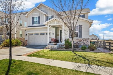 Craftsman house featuring board and batten siding, driveway, stone siding, and fence