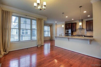 Kitchen with wall chimney range hood, wood finished floors, a breakfast bar, ornamental molding, and backsplash