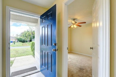 Carpeted entryway featuring baseboards and ceiling fan