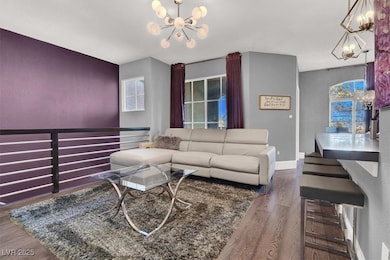 Living room with baseboards, a chandelier, and woo