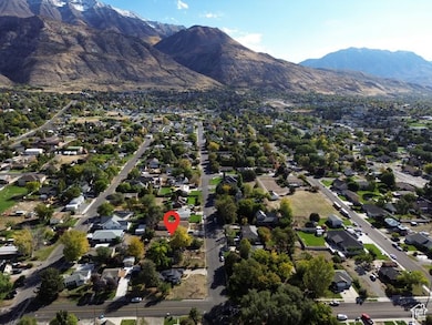 Aerial view of property and surrounding area featuring a mountainous background and nearby suburban area