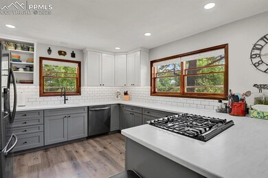 Kitchen with stainless steel dishwasher, gray cabinets, stovetop, fridge with ice dispenser, and light wood finished floors