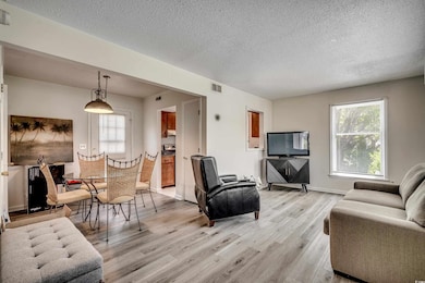 Living area featuring light wood finished floors, healthy amount of natural light, and a textured ceiling