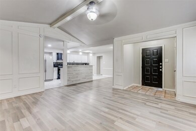 Unfurnished living room featuring light wood-type flooring, ceiling fan, sink, and vaulted ceiling with beams