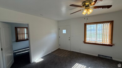 Carpeted foyer entrance featuring a ceiling fan and baseboards