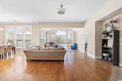 Living room featuring wood finished floors, baseboards, a healthy amount of sunlight, and a notable chandelier