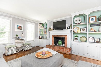 Living room with a brick fireplace, built in shelv
