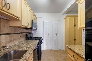 Kitchen featuring black appliances, light tile patterned flooring, light stone counters, and backsplash