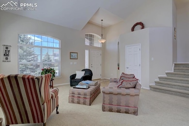 Carpeted living room featuring baseboards, high vaulted ceiling, and stairway