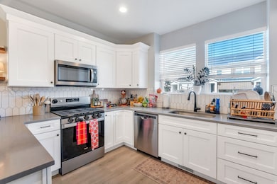 Kitchen with appliances with stainless steel finishes, tasteful backsplash, white cabinetry, open shelves, and recessed lighting