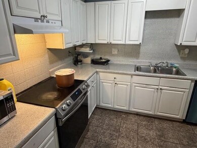 Kitchen with stainless steel appliances, light countertops, white cabinets, and under cabinet range hood