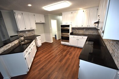Kitchen featuring double oven, sink, white cabinet