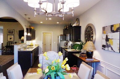 View from back of dining area that shows the gathering room to the left and the kitchen with area to the laundry room.